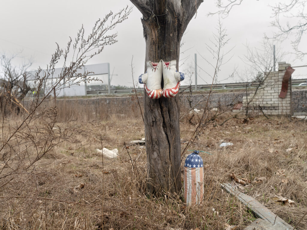 Au pied d'un arbre, des peluches et de petits objets ont été déposés dans une friche près d'un mur en ruine.