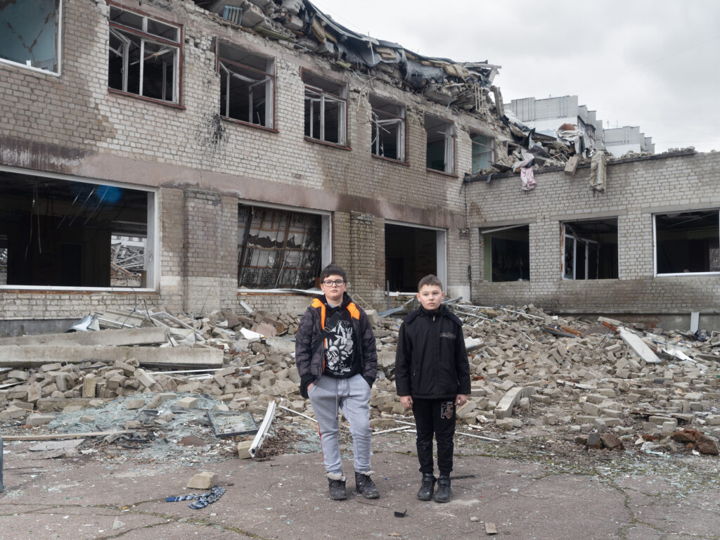 Deux enfants se tiennent devant leur école éventrée à Zhytomyr.